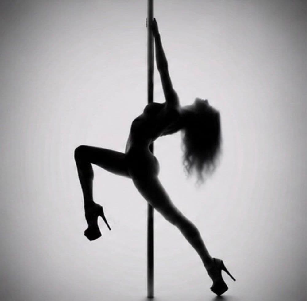 Silhouette d’une danseuse en talons, cambrée contre la barre
